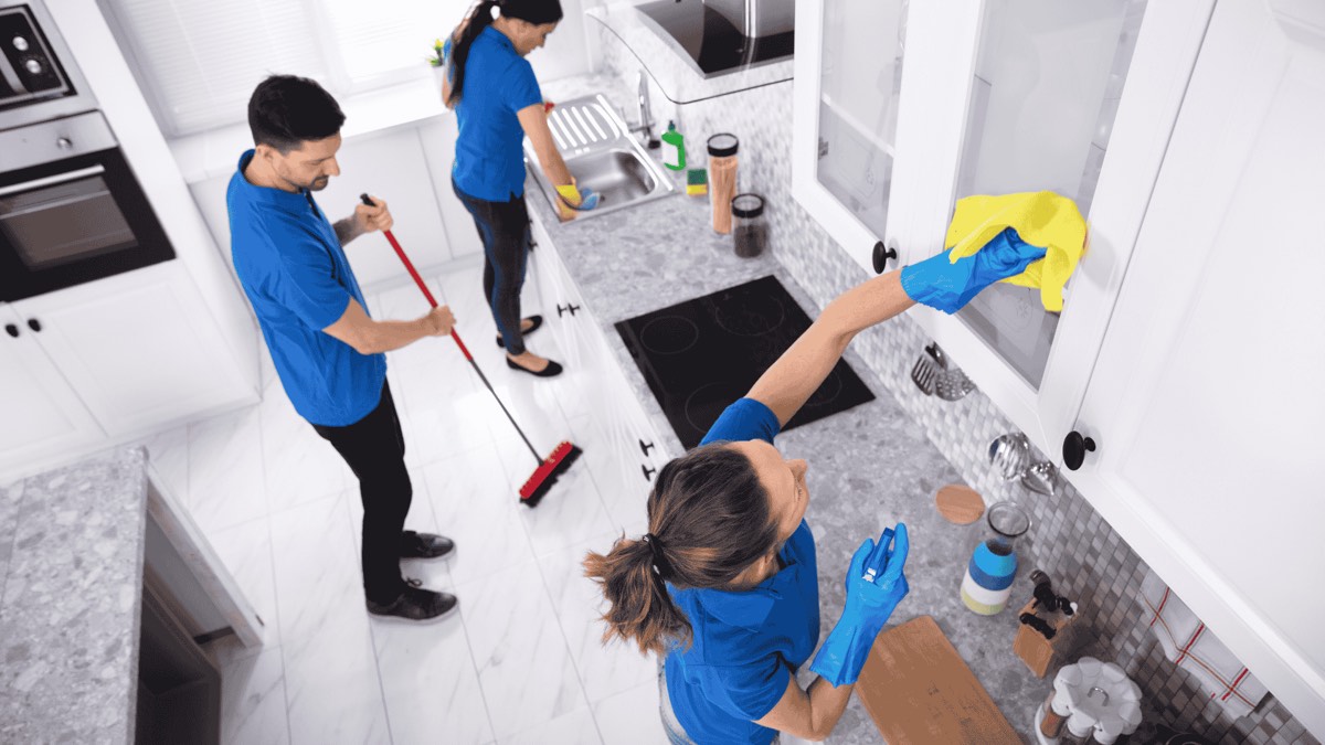Equipo de limpieza profesional preparando la cocina de un apartamento turístico