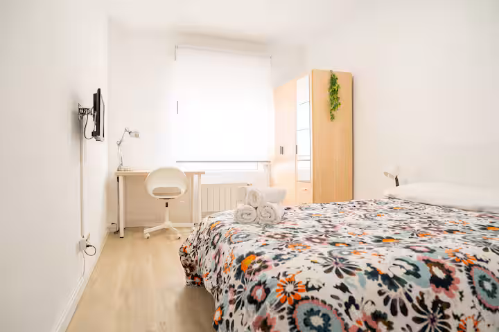 Habitación con cama de 135, mesa de estudio y ventana al patio en Torrelavega