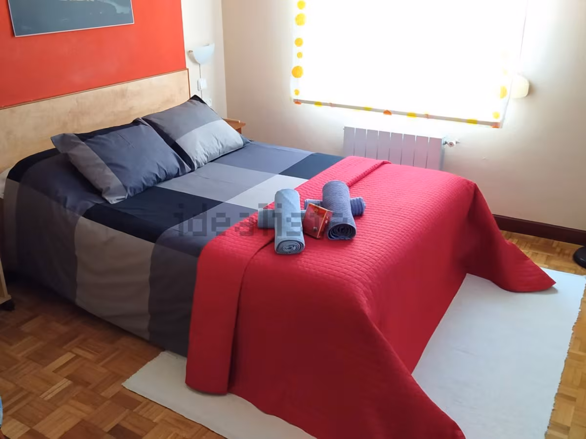 Dormitorio antes de la reforma, con pared roja y cabecero de madera